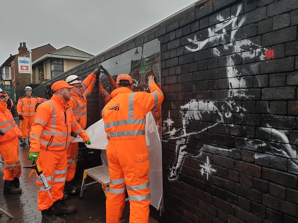 Workman fitting Banksy perspex in place