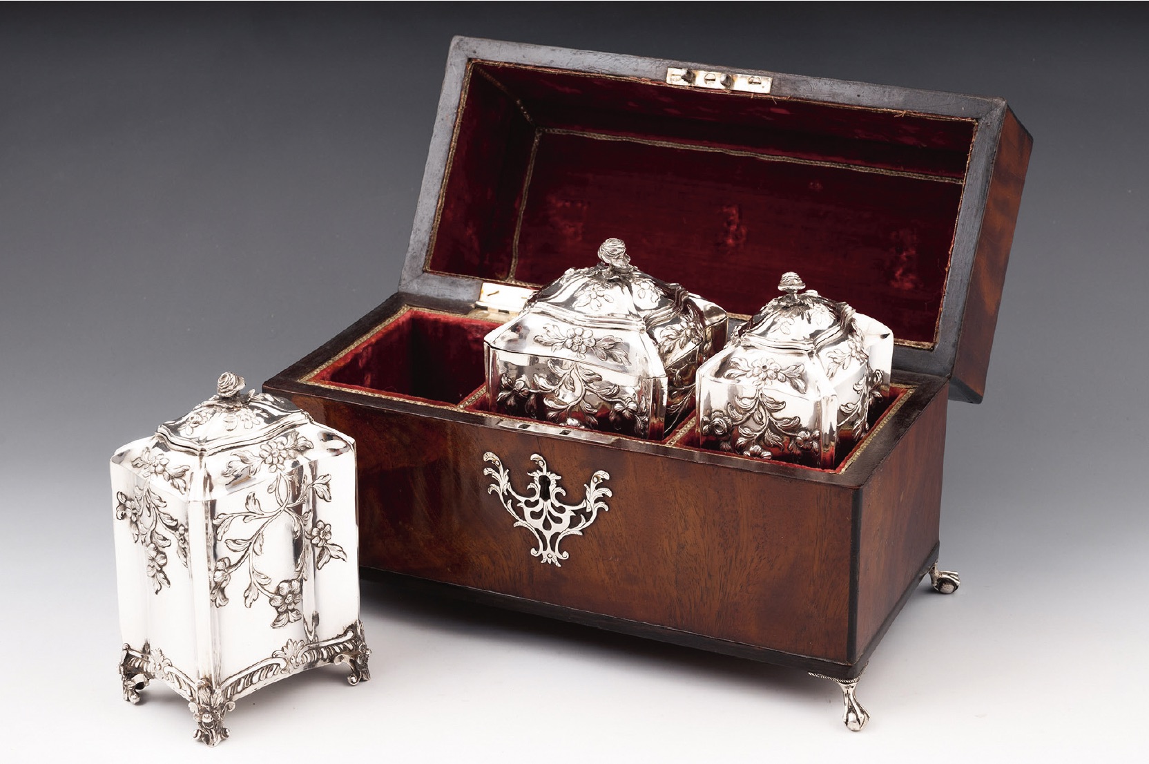 An antique mahogany tea chest containing two silver tea canisters and a larger sugar canister