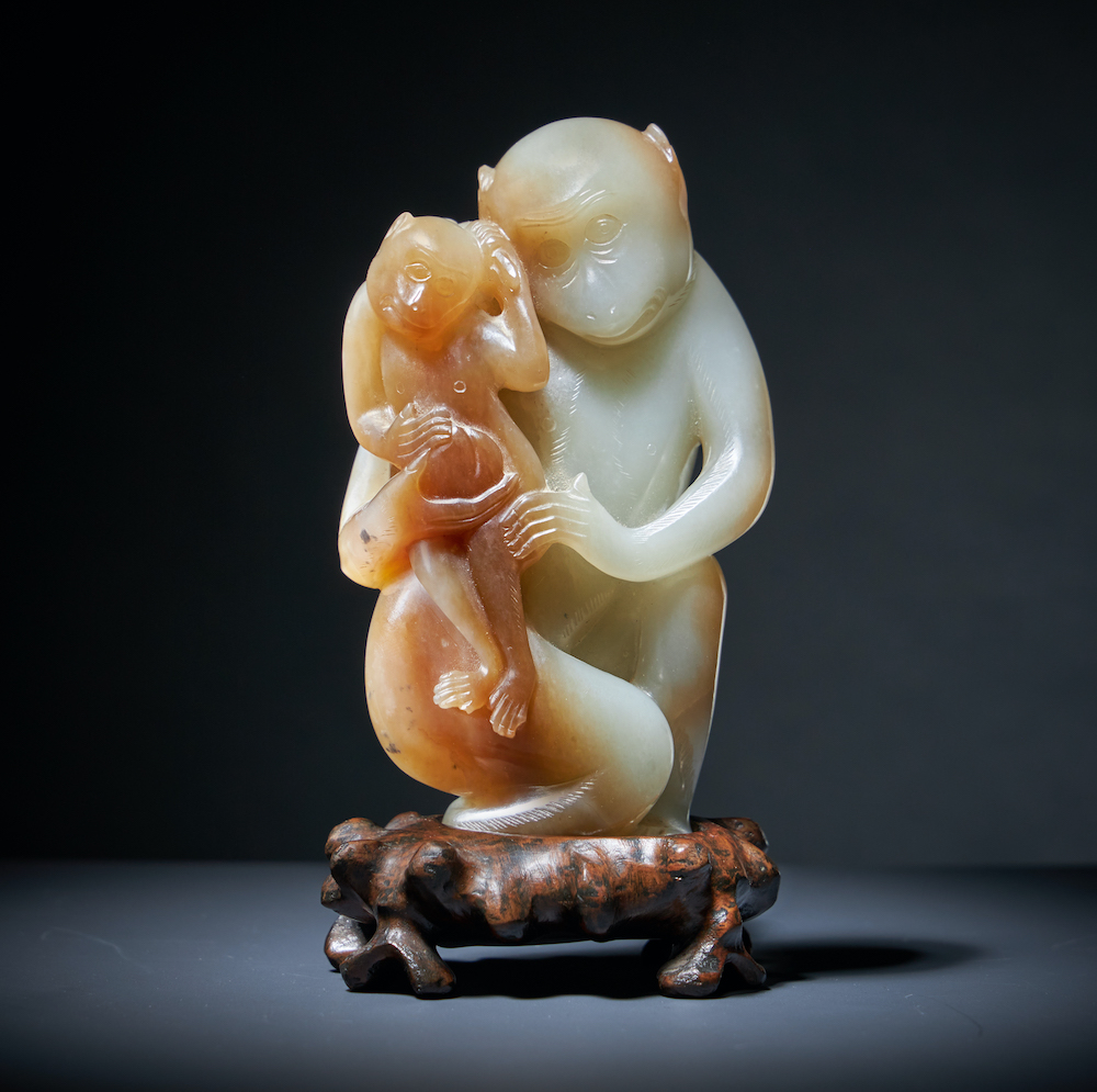 A Chinese pale celadon and brown jade model of a monkey from the Qing Dynasty