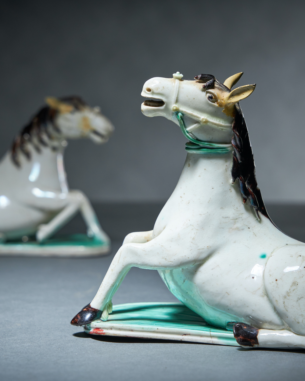 A pair of Chinese white glazed figures of horses, Kangxi