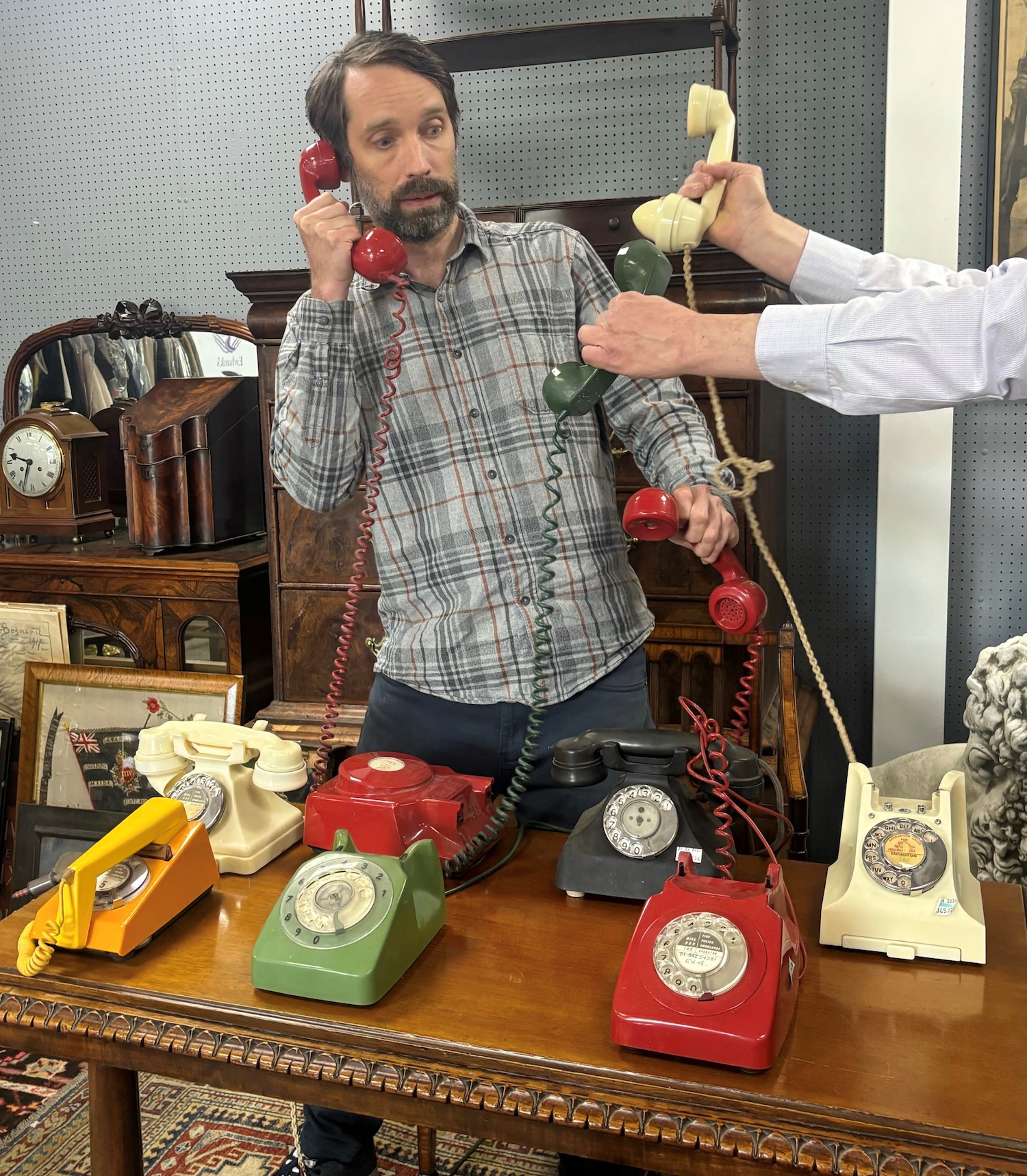 An auctioneer with a selection of vintage telephones