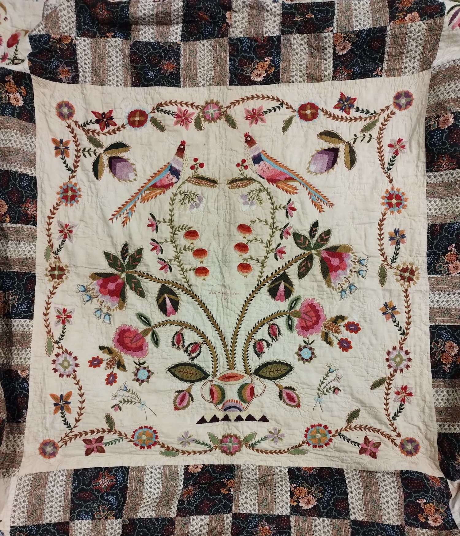 A detail of an antique quilt depicting birds and flowers