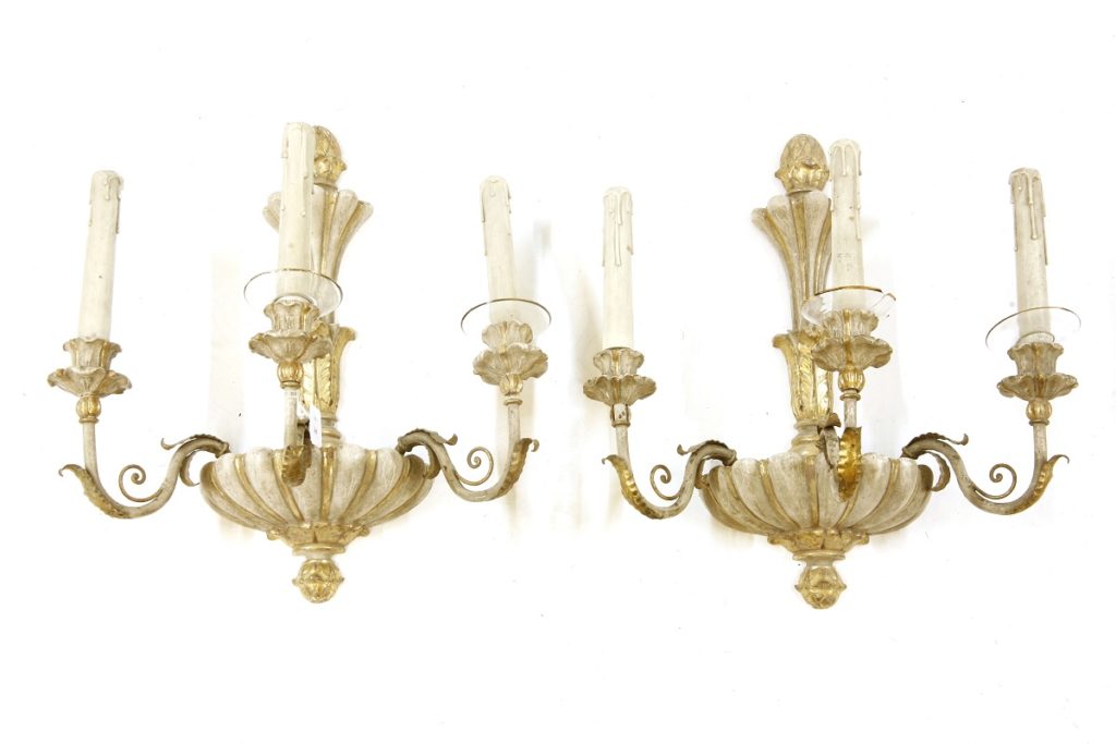 A pair of antique cream and gilt-painted three-branch wall lights